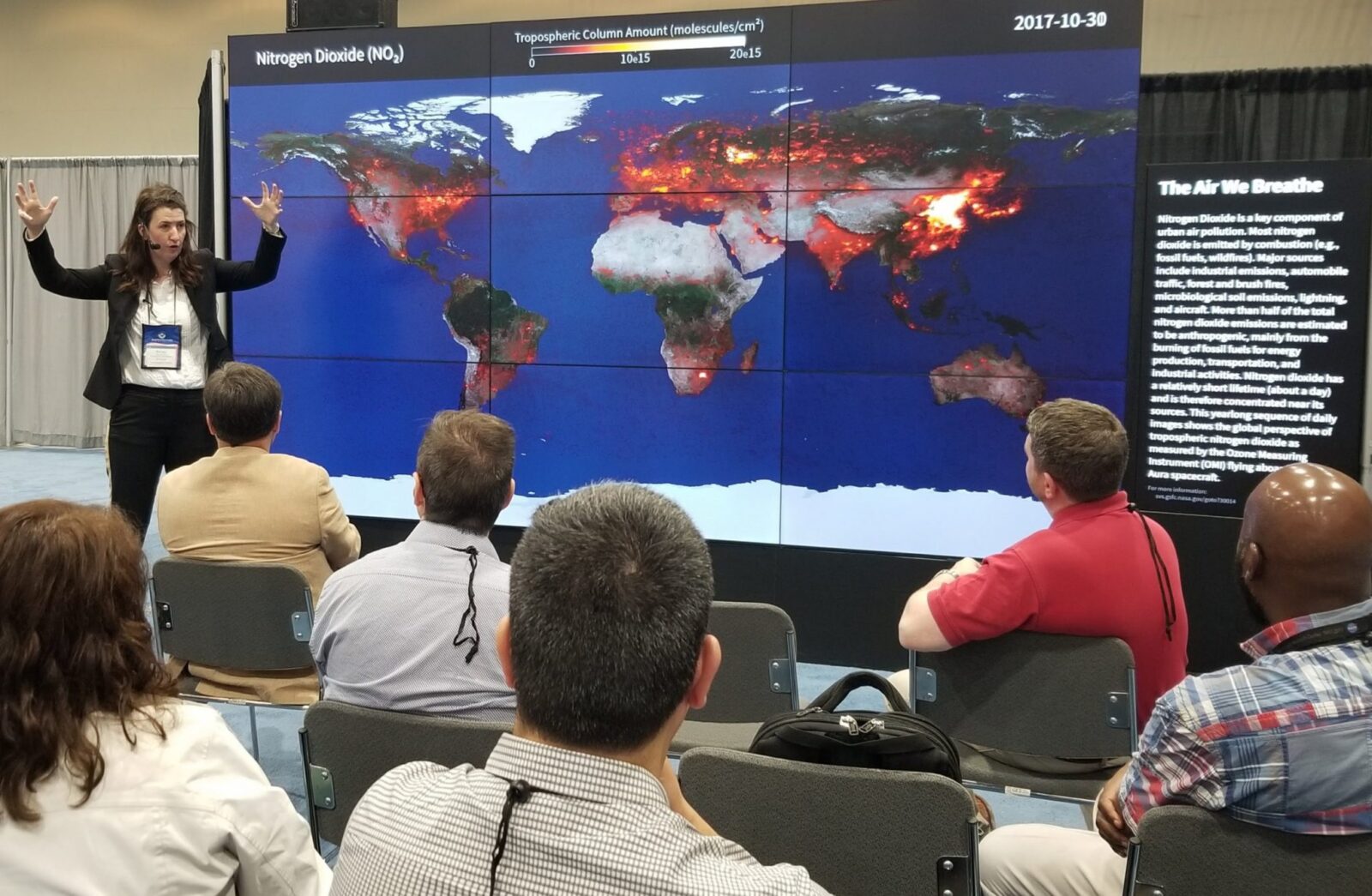 Woman in front of map depicting satellite data of nitrogen dioxide.