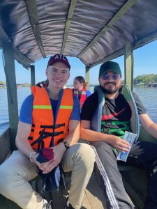 two men sitting in a boat with a cover wearing life jackets