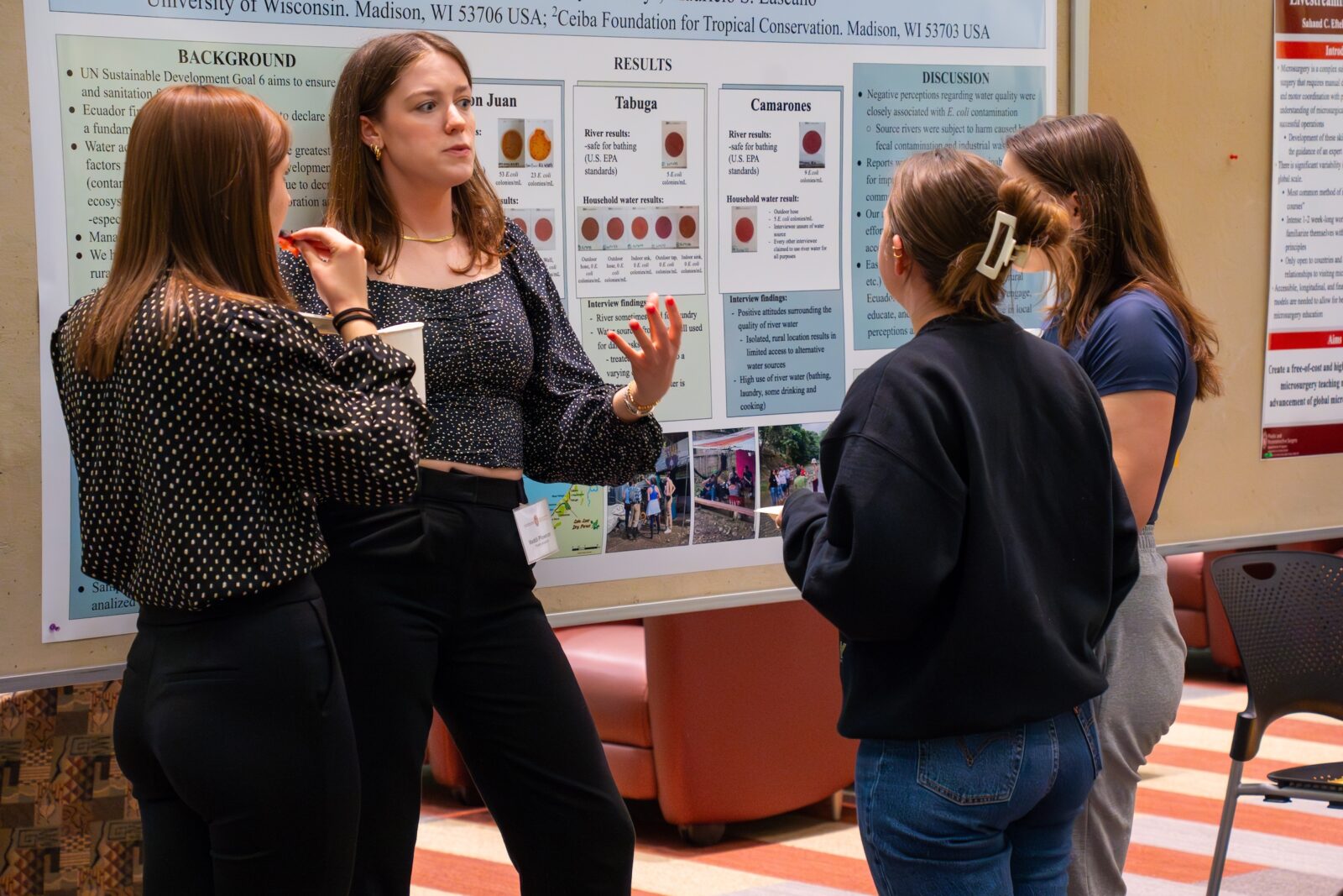 Four women standing and discussion a poster