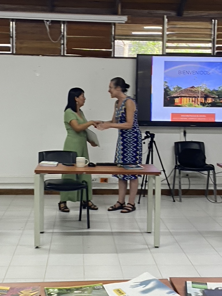 Hooz Angela Chaparro and Frances Vavrus shaking hands during group presentation, Sept 2023
