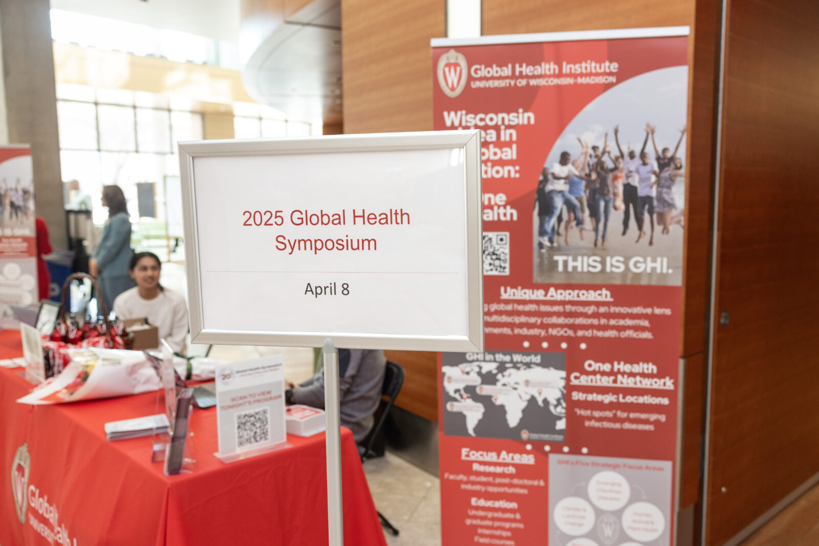 sign reading 20th Global Health Symposium, April 8 with red and white signage in the Discovery Building atrium