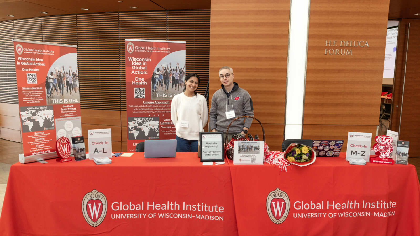 two people standing at a registration desk with red and white signage