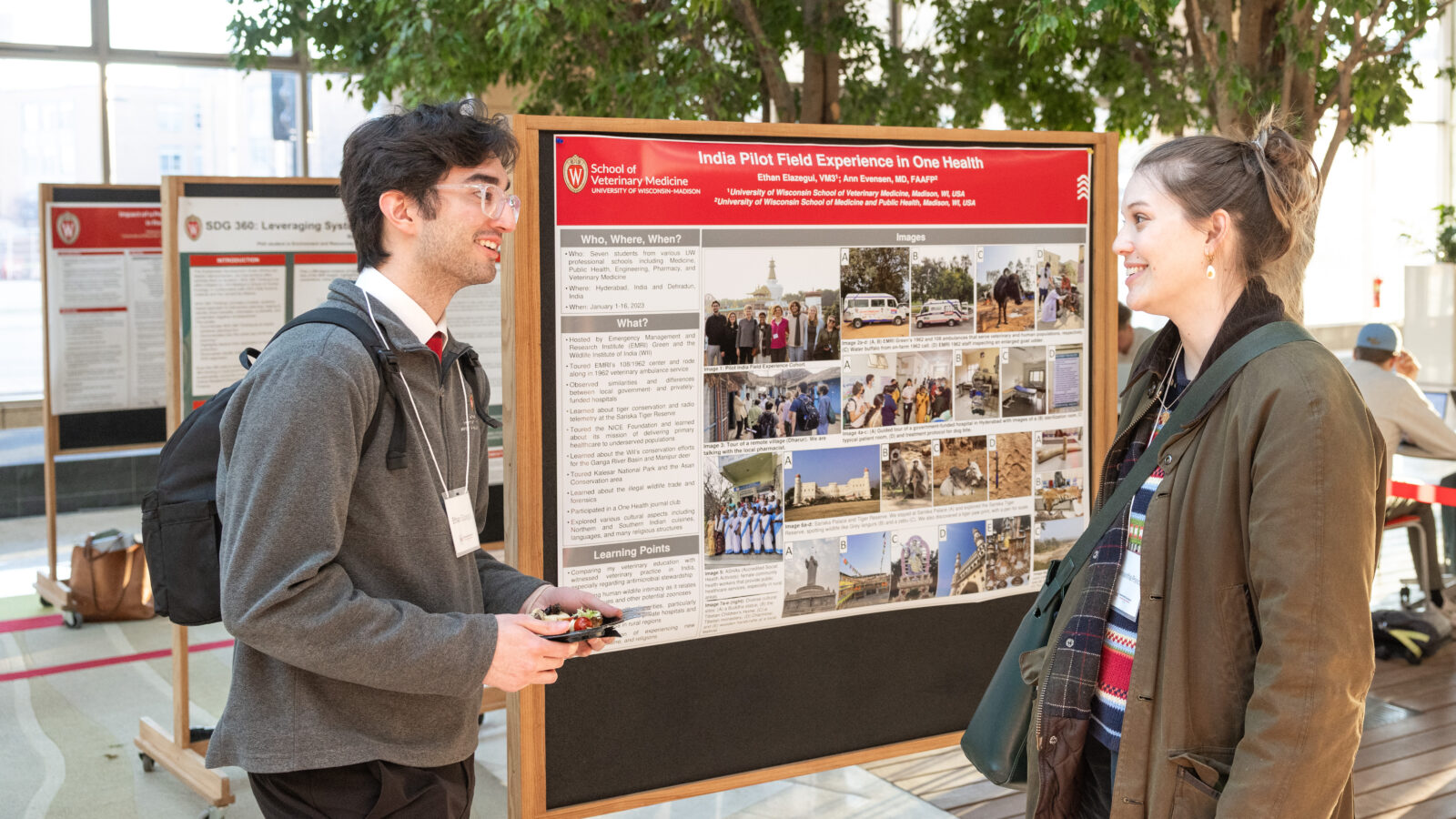 a man and a woman talking in front of a poster