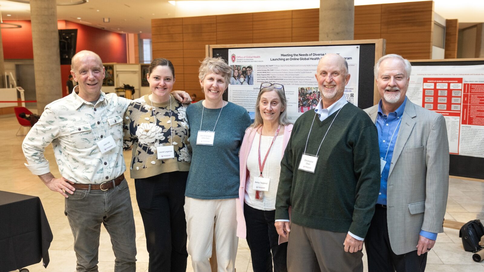 six people posting in front of a poster