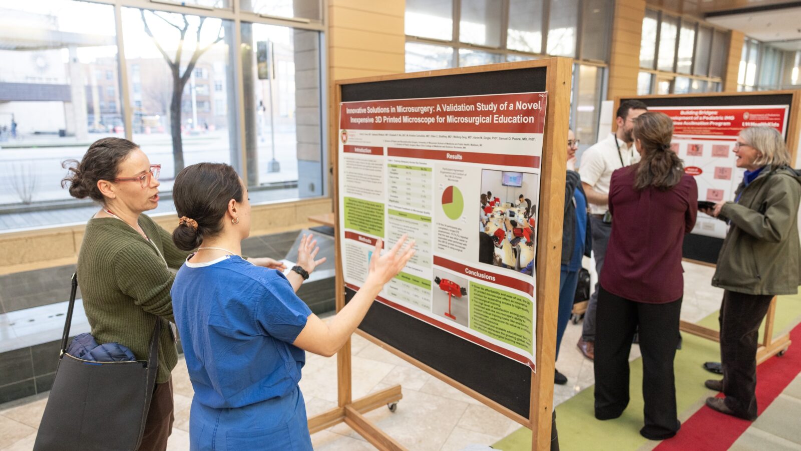 people standing and talking in front of posters in the Discovery building atrium