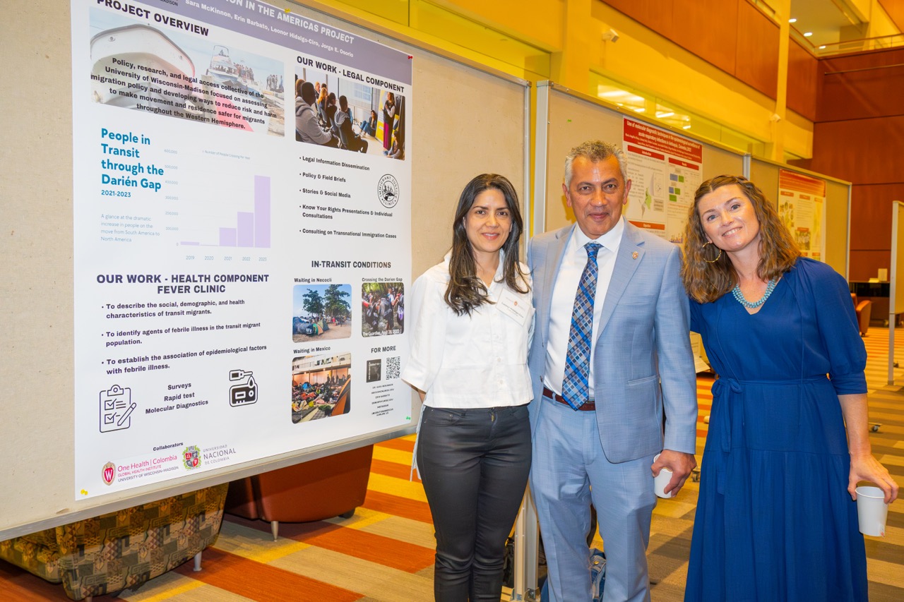 May 2024, two women and one man standing in front of a poster