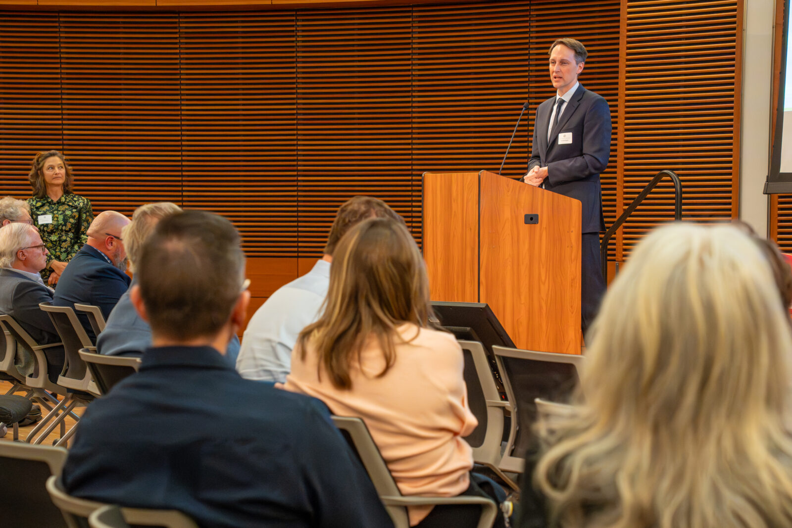 Photo from 2026 Global Health Symposium at the Discovery Building; Ryan Westergaard standing at lectern with sitting audience looking on