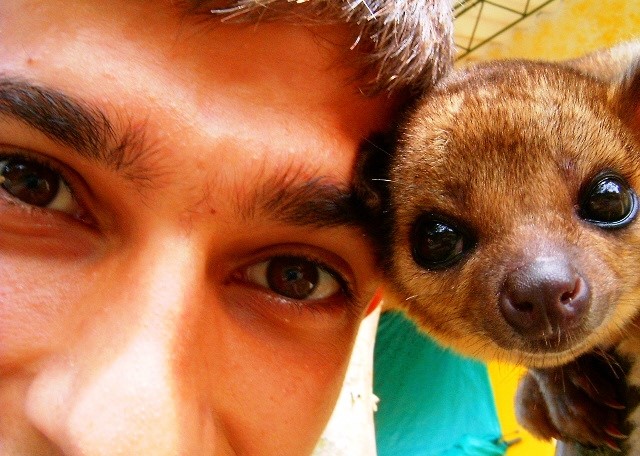 January 2024 From Treating to Preventing, a man with dark hair and eyes looking at camera with his head next to an animal with dark eyes and brown fur
