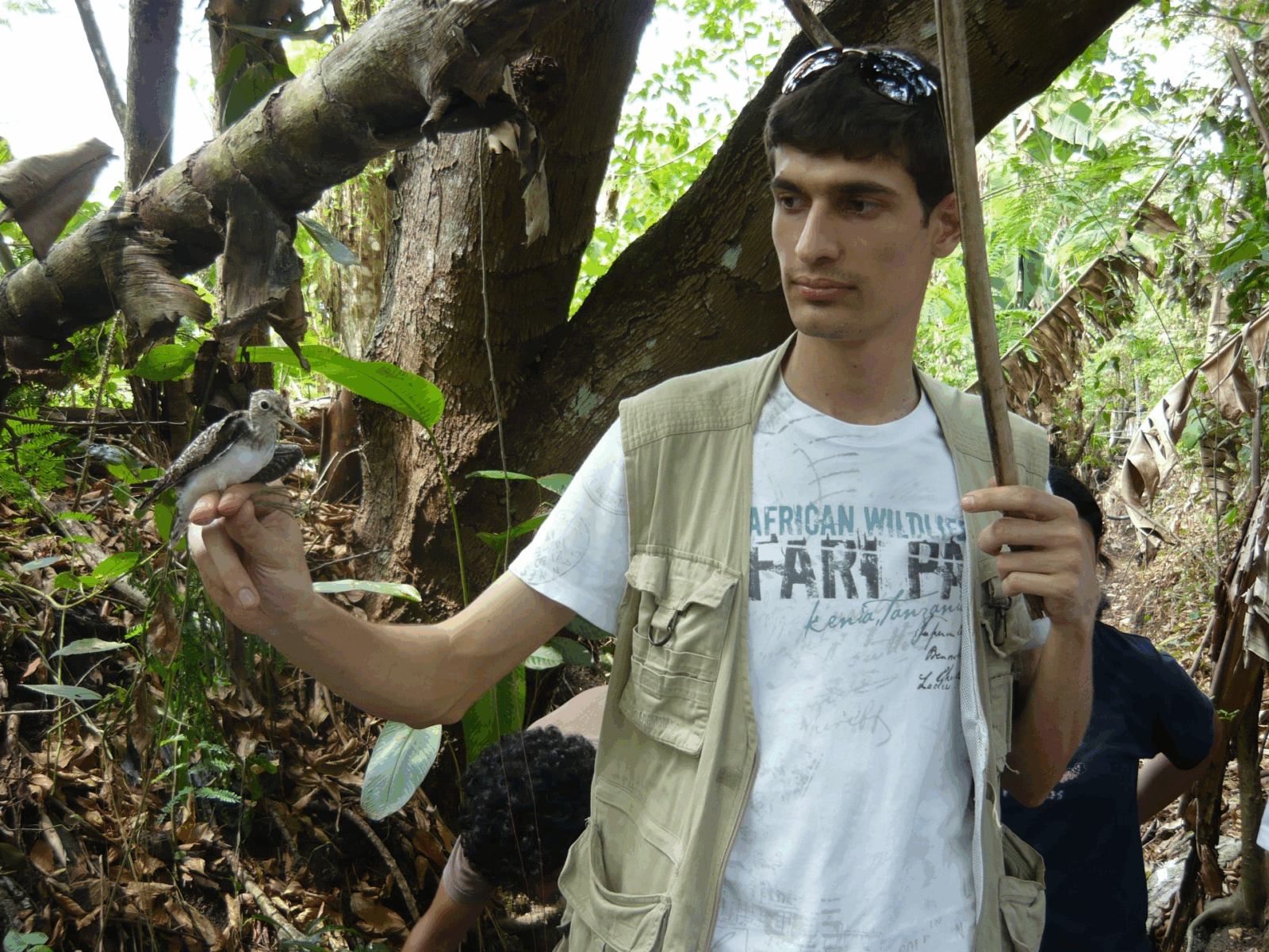 January 2024 From Treating to Preventing, man with dark hair, white shirt, tan vest in the woods