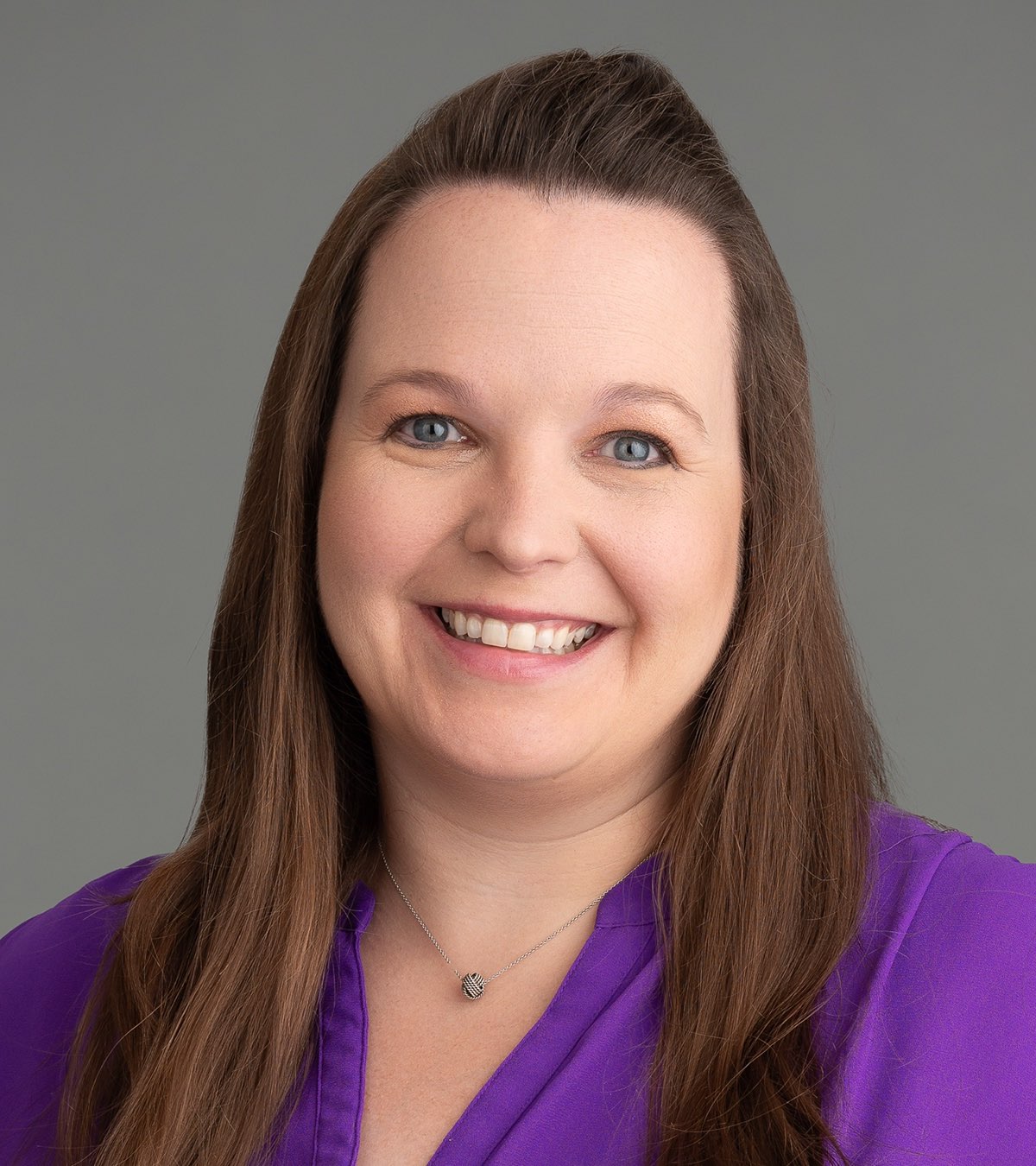 February 2024, woman with long dark hair, purple shirt against a grey background