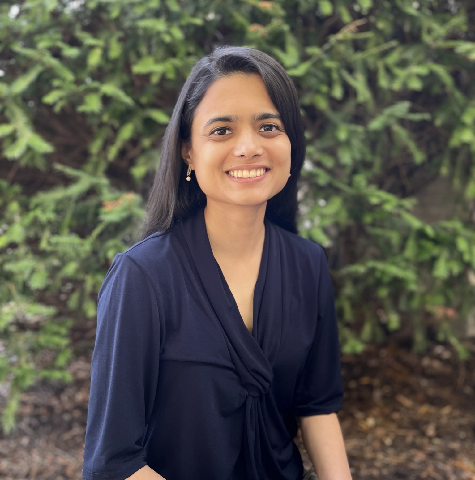 November 2023 Global Health Tuesday: Energy Challenges, woman with dark hair and dark shirt against a tree background