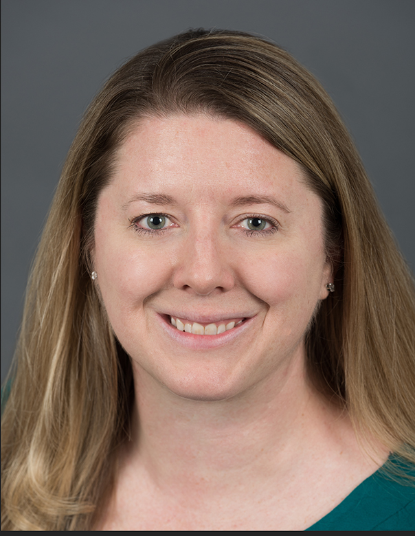July 2024, woman with light hair, green shirt against a dark grey background