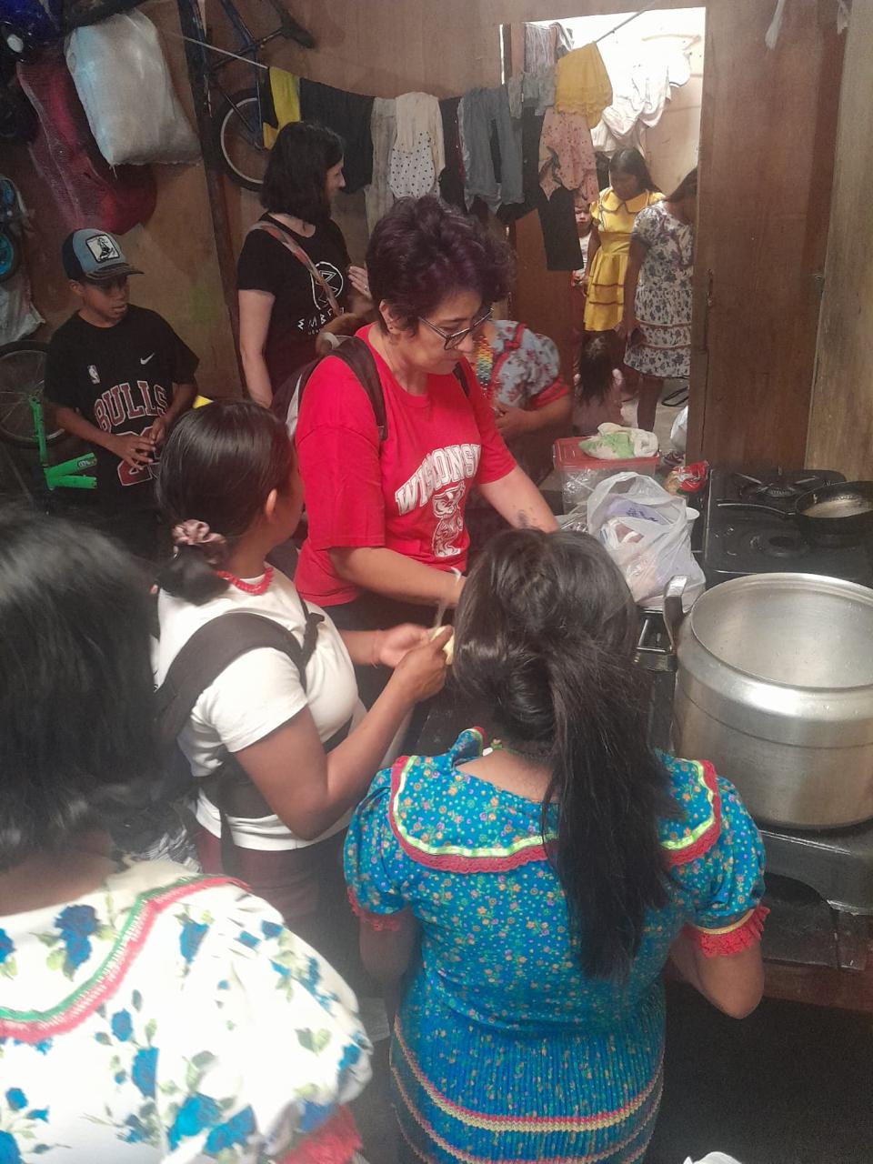June 2024, woman in red Wisconsin shirt cooking alongside  students with dark hair