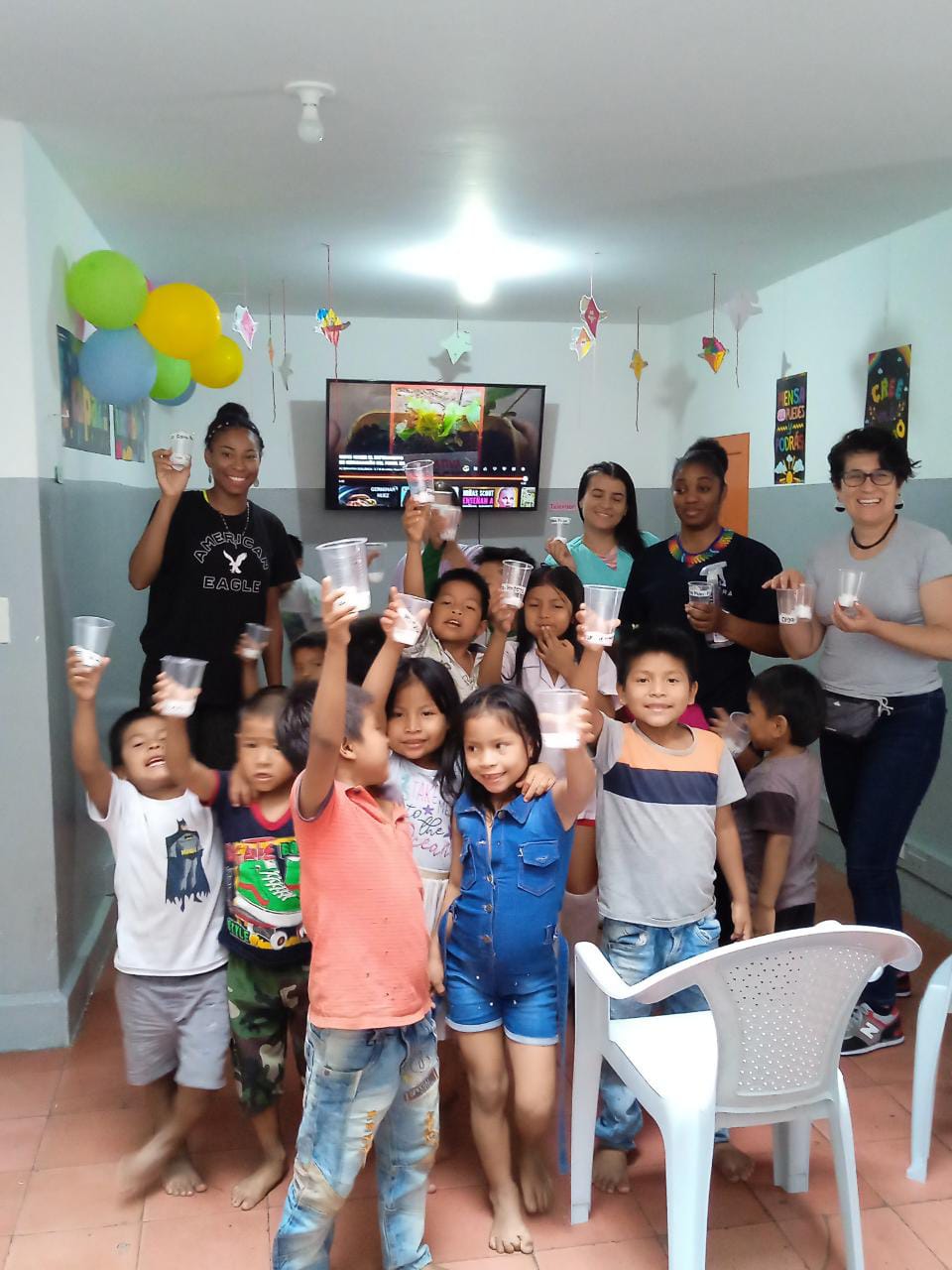 June 2024. group of women and children in a classroom setting, chilrfen are waiving 