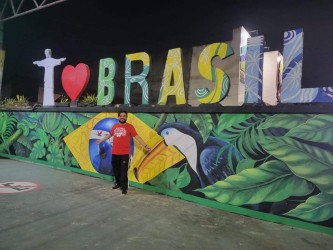 June 2024, man in front of a colorful mural with the world Brasil