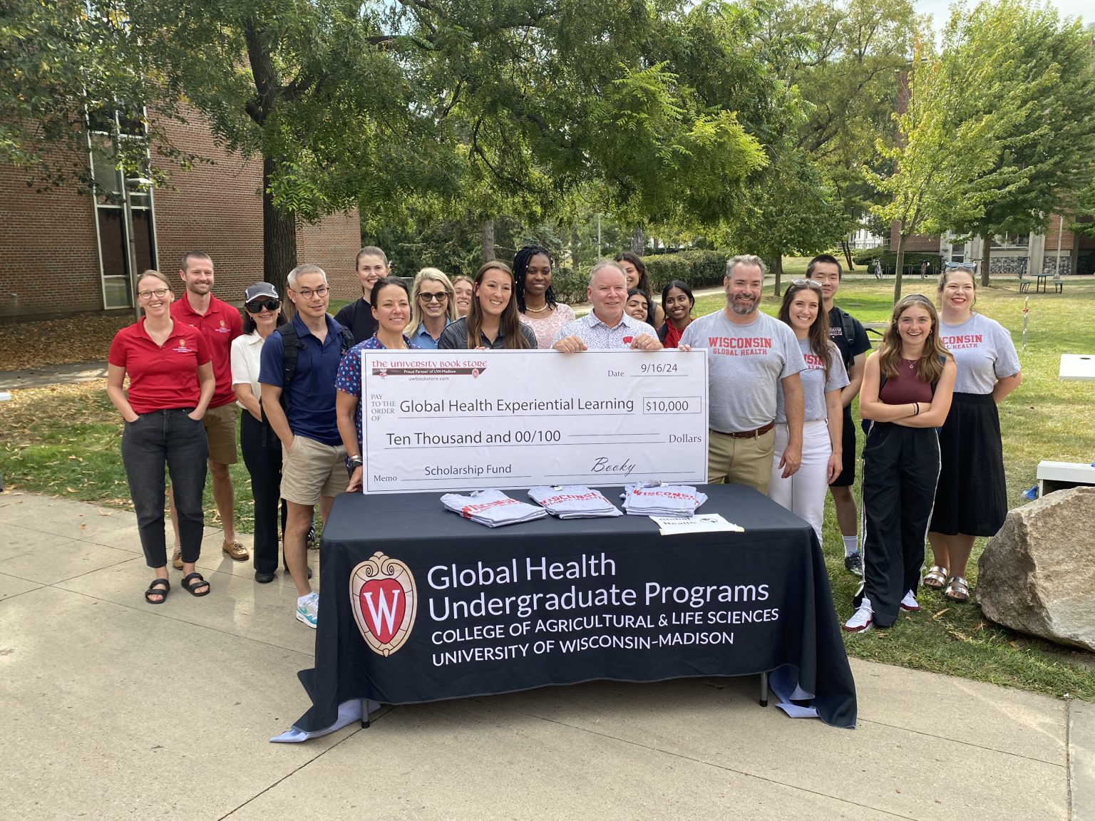 Group of people outside with a large check on top of a table