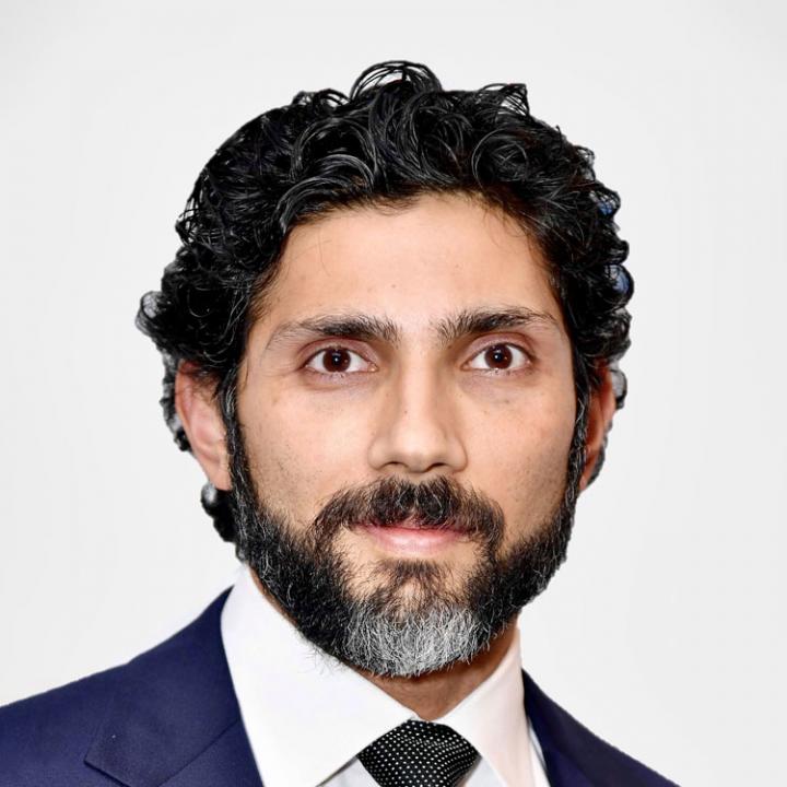 October 2024, man with dark hair and beard, blue jacket with white shirt and dark tie against a white background