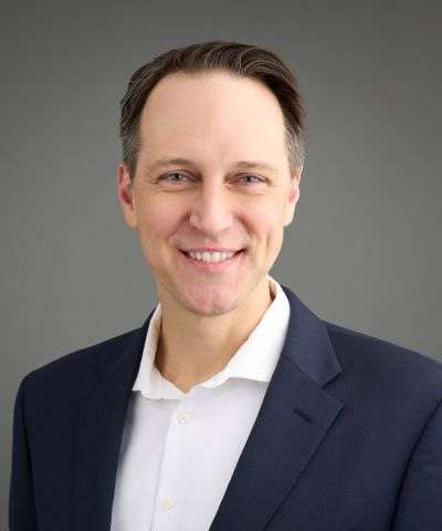 Ryan Westergaard headshot; man with dark hair, white shirt, dark jacked against a grey background