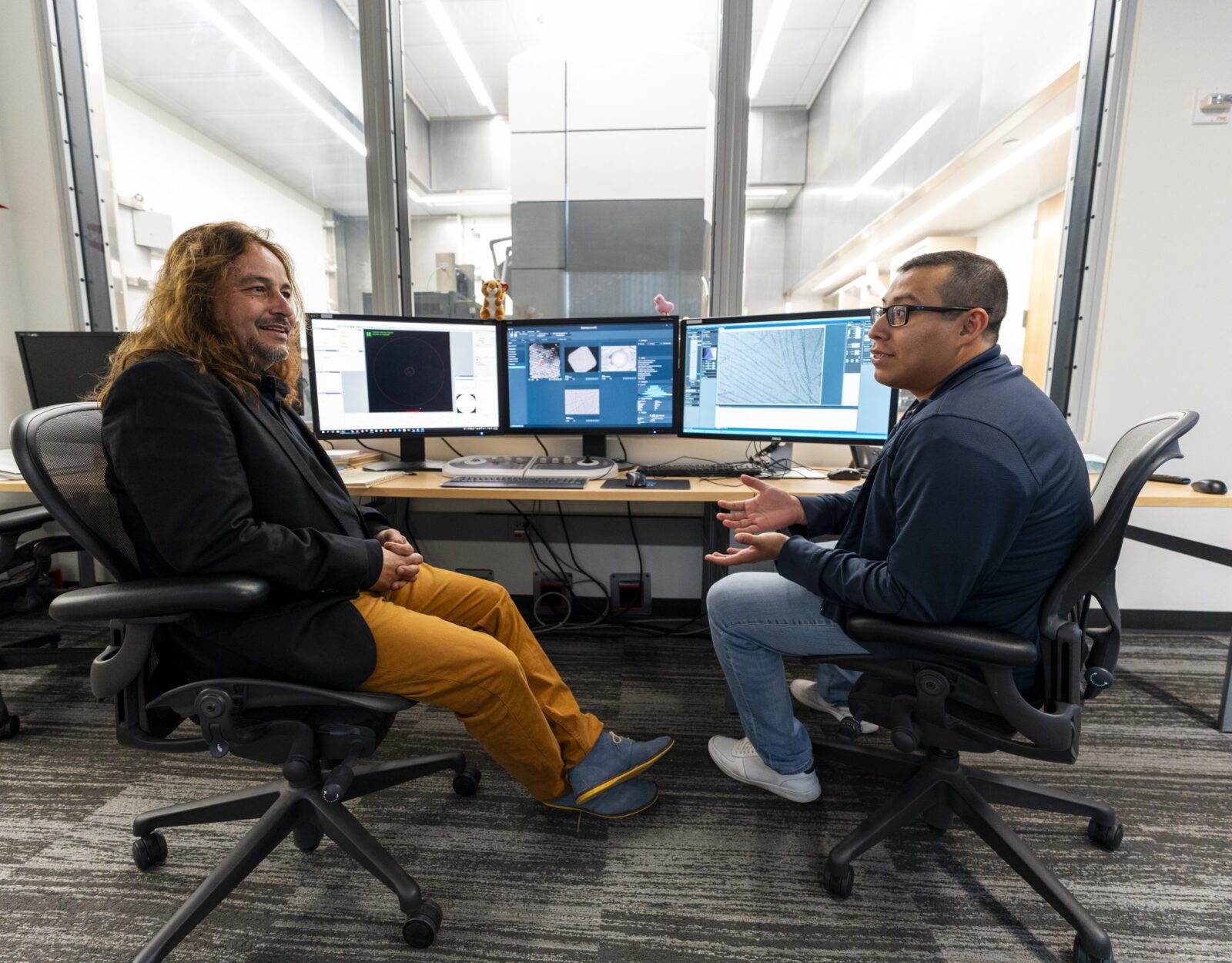 August 2024, two men siting in black swivel chairs with computers