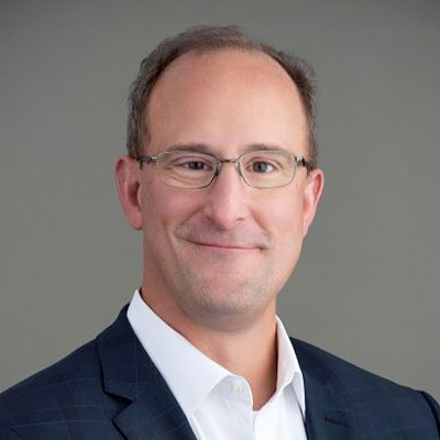 Man with darkish hair, glasses, white shirt and dark jacket against a grey background (headshot of Seth Dailey)