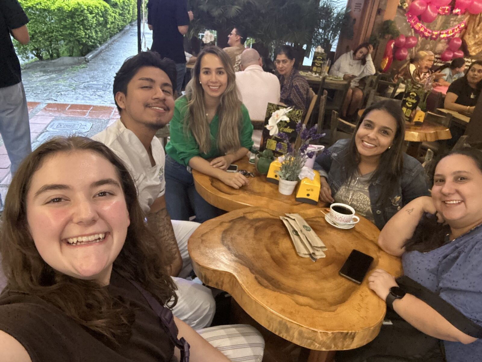 five people sitting at a wood table smiling