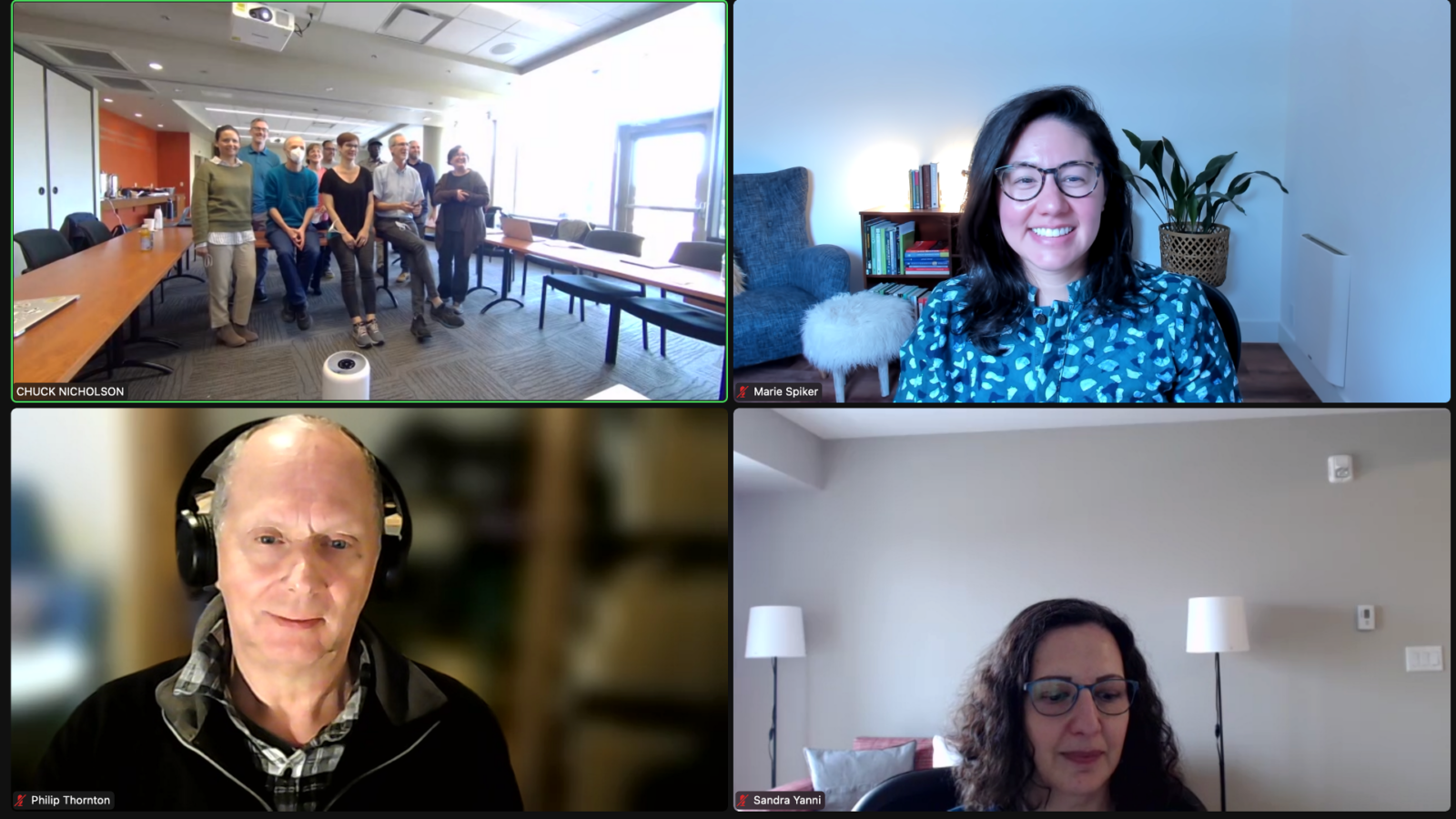 screenshot from a zoom meeting with four squares; one with multiple people, one with a bald man wearing headphones, one with a woman with dark hair and glasses smiling and one with a woman with dark hair and glasses with two lamps in the background
