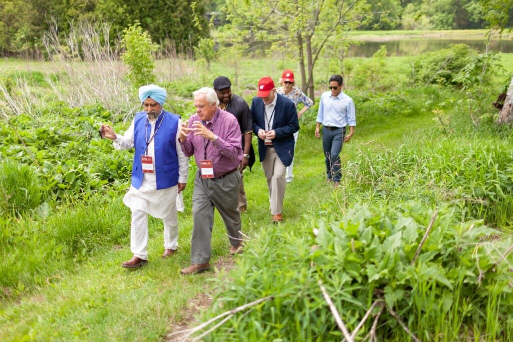 A group of six men walk through the prairie at Holy Wisdom monetary.
