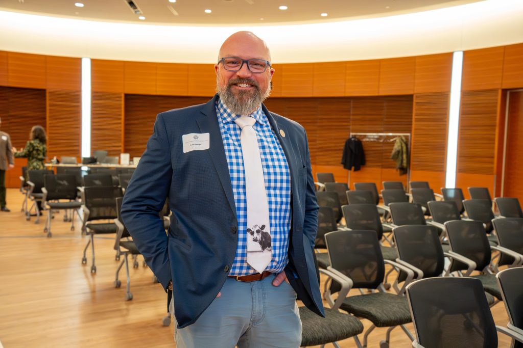 Photo from 2026 Global Health Symposium at the Discovery Building; Dr. Keith Poulsen in a suit with chairs in the background