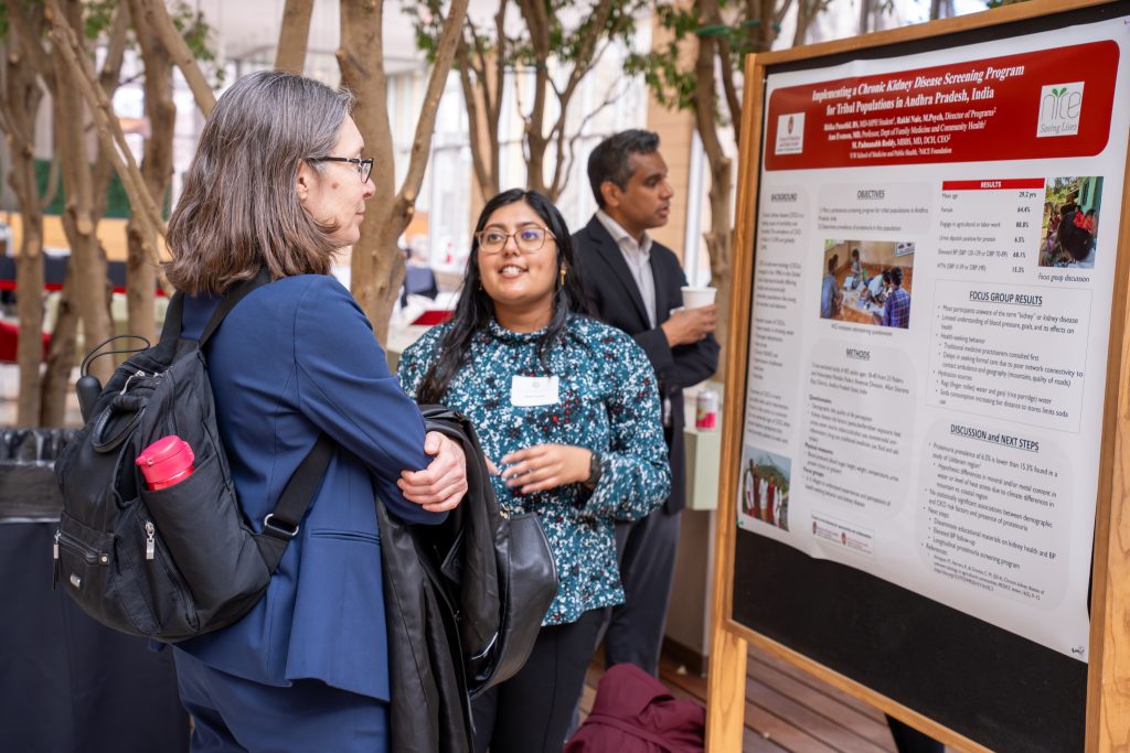 Photo from 2026 Global Health Symposium at the Discovery Building; Dr Vavrus with a student in a blue patterned shirt in front of a poster