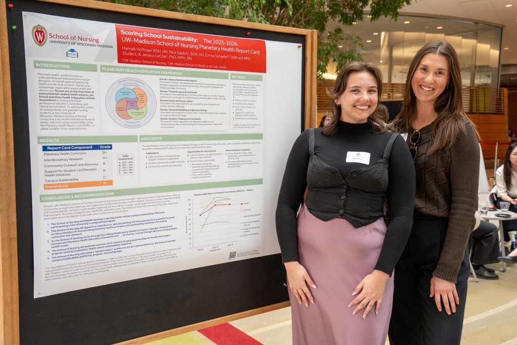Photo from 2026 Global Health Symposium at the Discovery Building; two women standing in front of a poster in the discovery building atrium