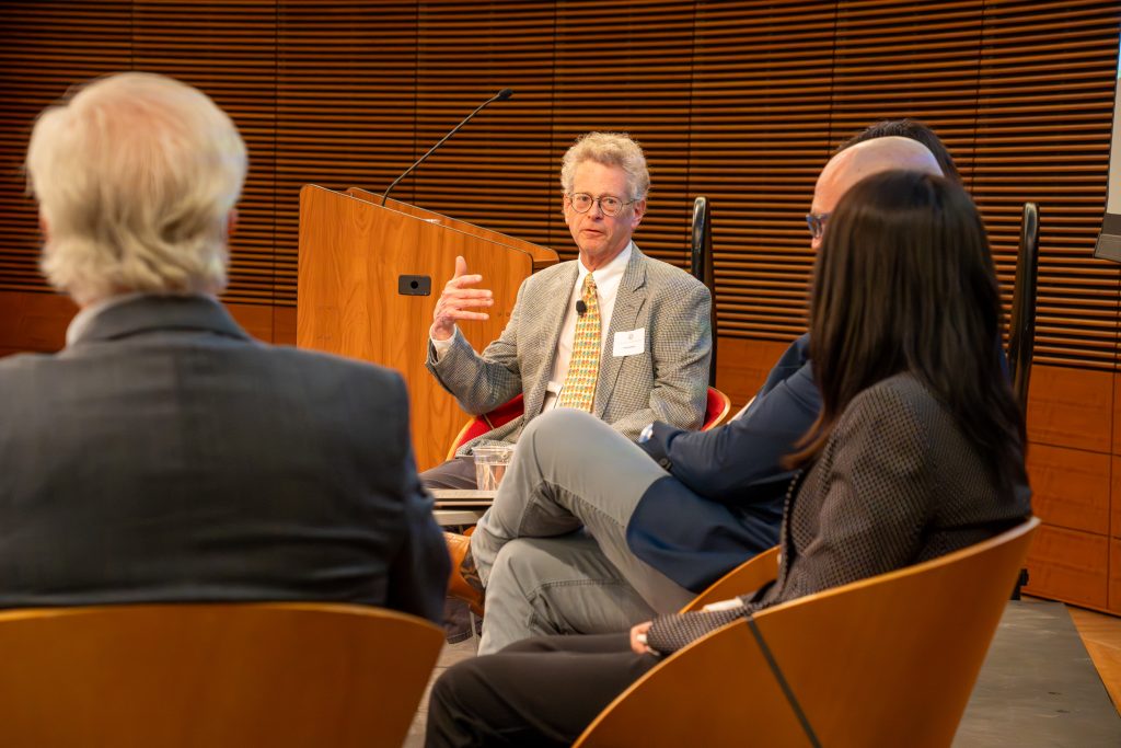 Photo from 2026 Global Health Symposium at the Discovery Building; Dr Hedberg on panel speaking with raised hand