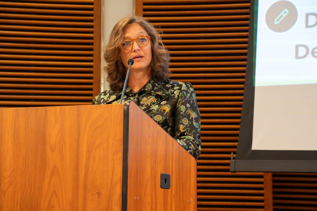 Photo from 2026 Global Health Symposium at the Discovery Building; Dr Kushner wearing a green and black jacket at the lecturn