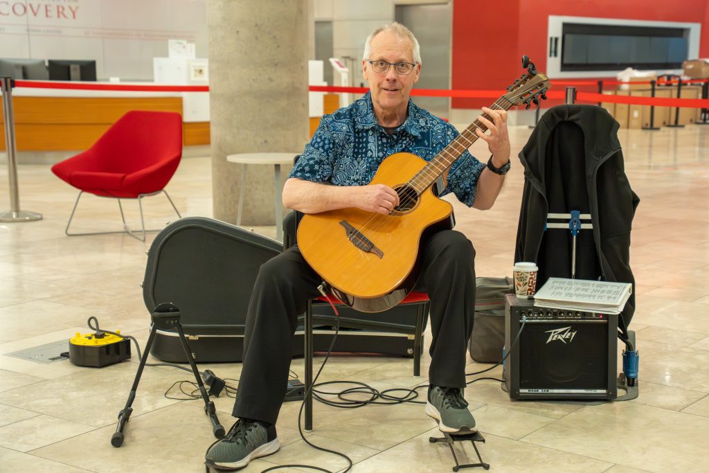 Photo from 2026 Global Health Symposium at the Discovery Building; guitarist Steven Meyer sitting with his guitar